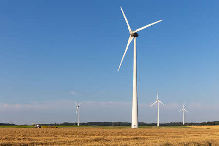 Ggroup of wind generators in a harvested field with a tractorの写真素材