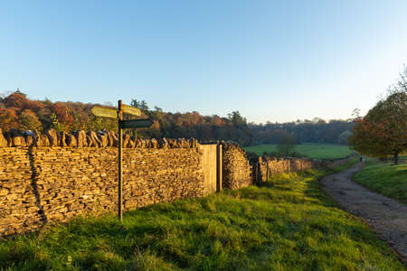 A path for a quiet autumn walk in the UK countryside with the evening sun on a stone wallの写真素材