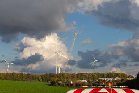 flashing lights of a working car and installation of new wind turbines and a beautiful cloudy sky in the backgroundの写真素材