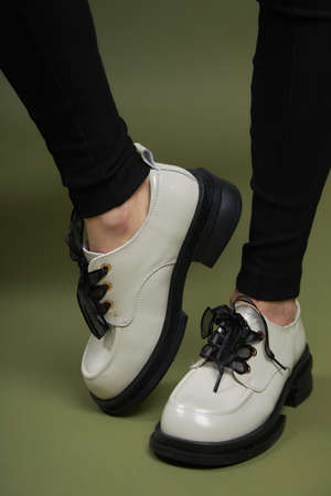 Female legs in black boots on green background. Casual lifestyle concept photo. Fashion shoes made of eco-leather spring-summer 2022.の写真素材