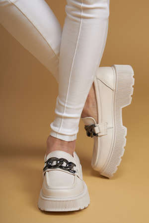 Perfect female legs.  Beautiful female legs in summer shoes in white designer pants on a yellow  background.の写真素材