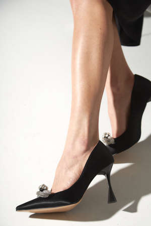 Woman taking off black evening shoes. Long slim beautiful female feet in footwear, isolated on a white background.の写真素材