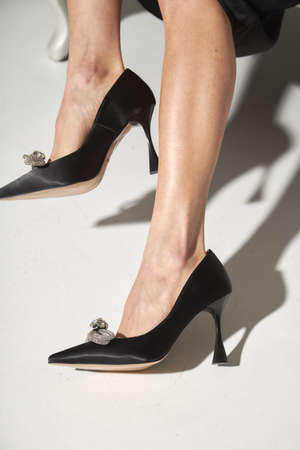 Woman taking off black evening shoes. Long slim beautiful female feet in footwear, isolated on a white background.の写真素材