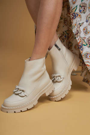 Fashionable woman with beige boots, leather shoes, studio shot. Casual lifestyle concept photo on a yellow pastel background.の写真素材