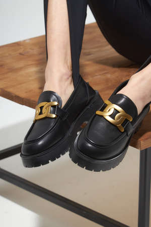 Beauty stylish woman posing in fashion clothes in studio. Summer fashion, trendy shoes, casual style. Woman chooses shoes collection autumn spring 2022. Long slim beautiful female feet. Sexy fashion model woman legs with black shoes on white background.の写真素材