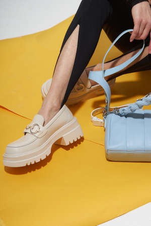 Sexy fashion model woman legs with shoes on sunny background. Fashion girl legs portrait on yellow background. Summer fashion, trendy bag and shoes, casual style. Fashionable handbag and shoes setの写真素材