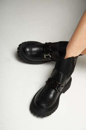 Black street sneakers on the women's legs. Comfortable and beautiful black shoes on white background.の写真素材