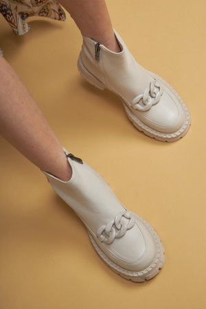 Fashionable woman with beige boots, leather shoes, studio shot. Casual lifestyle concept photo on a yellow pastel background.の写真素材