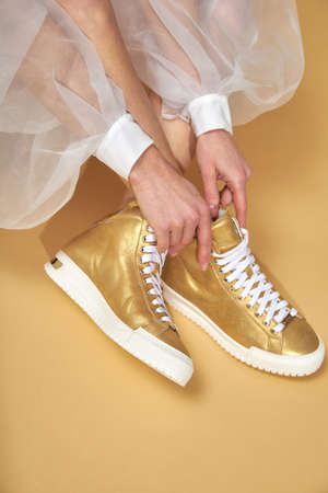 Fashionable woman with beige boots, leather shoes, studio shot. Casual lifestyle concept photo on a yellow pastel background.の写真素材