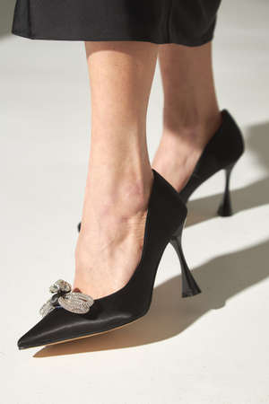 Female legs in black leather shoes from the new collection on a white sunny background. Fashion shoes made of eco-leather spring-summer 2022. Close-up mockupの写真素材