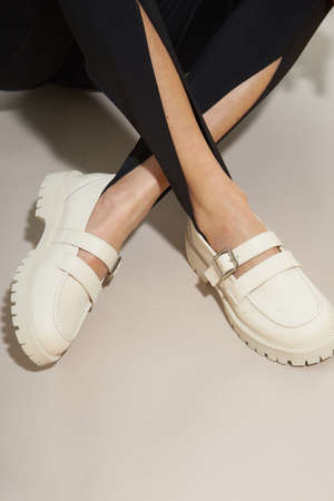 Woman chooses shoes collection autumn spring 2022. Long slim beautiful female feet. Sexy fashion model woman legs with black shoes on sunny background. Fashion model girl legs portrait on pastel background. Beauty stylish woman wear woman posing in fashion clothes in studio. Summer fashion, trendy bag and shoes, casual style.の写真素材
