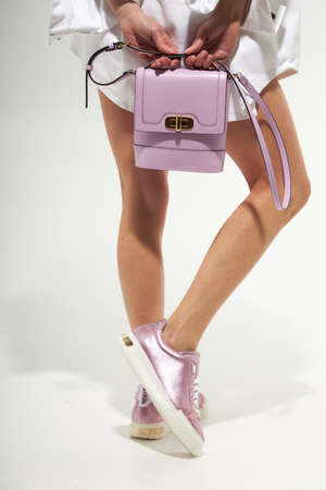 Fashion model girl legs portrait on white background. Beauty stylish woman wear woman posing in fashion clothes in studio. Summer fashion, white coat, trendy bag and shoes, casual style.Fashionable handbag and shoes setの写真素材