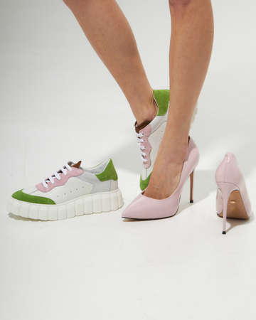 Fashion model girl legs portrait on white background. Beauty stylish woman posing in fashion clothes in studio. Summer fashion, trendy shoes, casual style. Woman chooses shoes collection autumn spring 2022. Long slim beautiful female feet.の写真素材