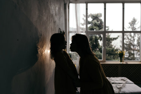 mom kisses daughter in the sunset backlightの写真素材