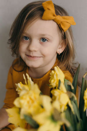 little girl in a yellow dress with a beautiful bouquet of narcissus flower