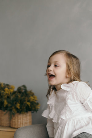 little girl in a yellow dress with a beautiful bouquet of narcissus flowerの写真素材