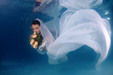Bride with flowers in underwater for wedding in a poolの写真素材