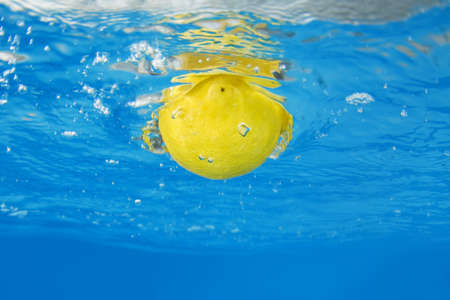 Lemon splashing in blue waterの写真素材