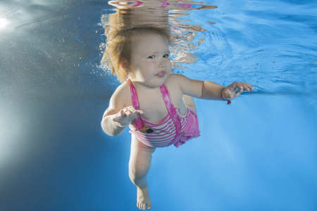 little girl learns to swim underwater in the poolの写真素材