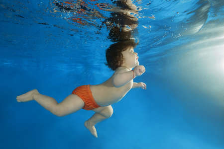 little boy learns to swim underwater in the pool