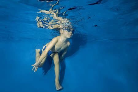 4 years boy in swimming goggles play under water in the poolの写真素材