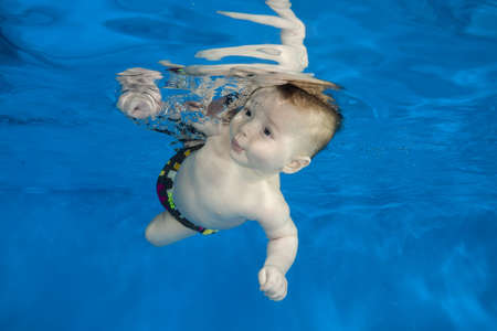 little 4 months boy learns to swim underwater in the pool