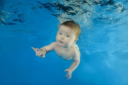 Little boy learns dives underwater in the pool
