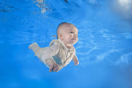 3 months boy in dress learning to swim underwater in the pool 