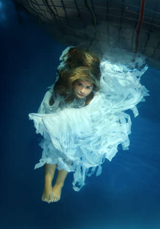Young beautiful woman in the image of an angel underwaterの写真素材