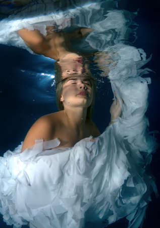 Young beautiful woman in the image of an angel underwaterの写真素材