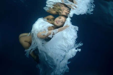 Young beautiful woman in the image of an angel underwaterの写真素材