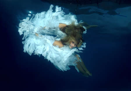 Young beautiful woman in the image of an angel underwaterの写真素材