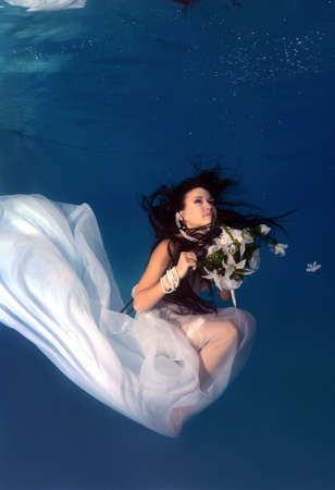 Bride in a wedding  with flowers underwater in the pool. Underwater wedding の写真素材