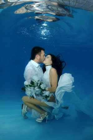 The bride and groom kiss underwater in the pool. Underwater wedding の写真素材