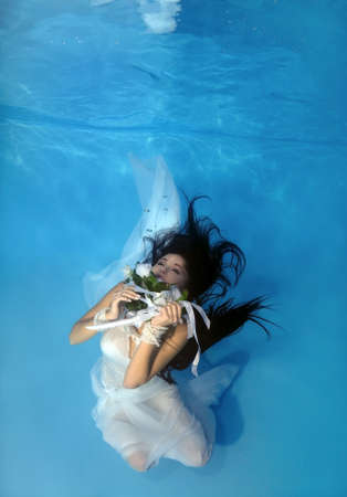 Bride in a wedding  with flowers underwater in the pool. Underwater wedding の写真素材