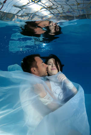 The bride and groom kiss underwater in the pool. Underwater wedding の写真素材