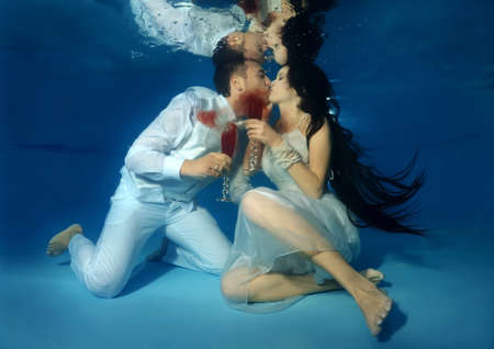 The bride and groom kiss underwater in the pool. Underwater wedding の写真素材