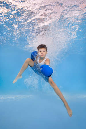 A boy in boxing gloves posing underwater in the poolの写真素材