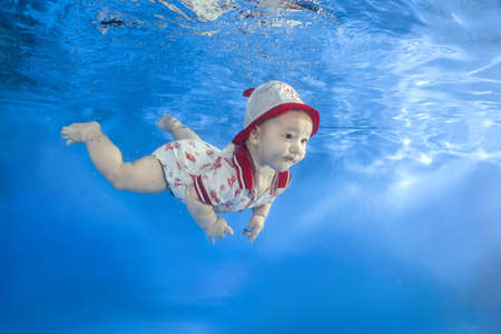 A little boy in a red cap is swimming in the poolの写真素材