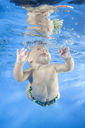 4 months boy dives underwater in the poolの写真素材