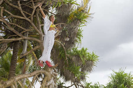 Woman on the beach standing on palm tree and on an exotic tropical islandの写真素材