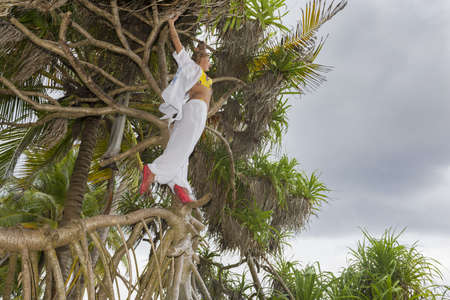 Woman on the beach standing on palm tree and on an exotic tropical islandの写真素材