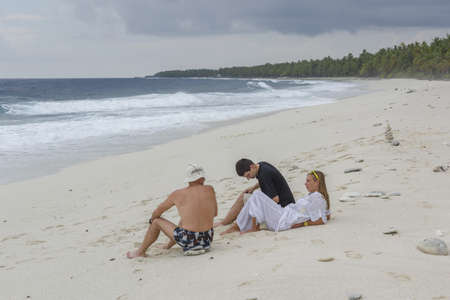 Group of friends chatting on a beautifu tropical sandy beach. Rest on an exotic tropical island, on a deserted beachの写真素材