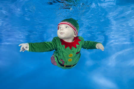 Little boy dressed as a gnome underwater on a blue water background.  Healthy family lifestyle and children water sports activity. Child development, disease preventionの写真素材
