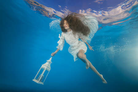 White angel with a flashlight underwater. Underwater girls picturesの写真素材
