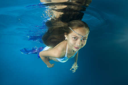 A girl in a mermaid costume poses underwater in a pool. Underwater girls picturesの写真素材