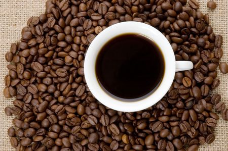 Coffee beans and white cup on the textured background