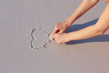 Drawing on white sand beach heart symbol, handsの写真素材