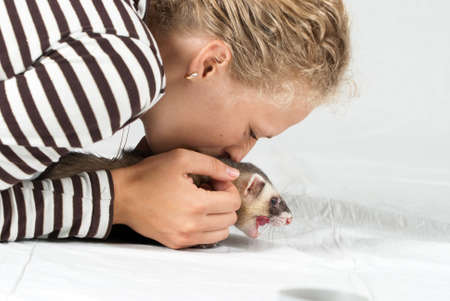 Woman playing with polecat in studio on white backgroundの写真素材