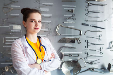 portrait of a doctor on a stand background with a surgical instrument. Concept young student girl studying a medical tool.の写真素材